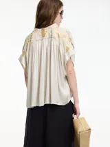 Blusa negra de manga corta con escote en V y bordados en la espalda.