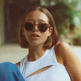 Lentes de sol con montura redonda de madera color marrón y lentes verdes.