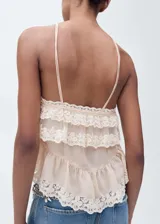 Top color crema con tirantes finos, ribetes de encaje, detalle de volantes en el cuello y en el bajo.