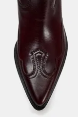Bota de cuero color borgoña, estilo cowboy, con puntera fina y tiradores laterales.