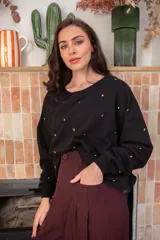 Sweater blanco de algodón con cuello redondo y mangas largas. Decorado con tachas plateadas en el frente y las mangas.