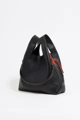Bolso de mano negro marca Bimba y Lola, modelo Paper M, confeccionado en piel vacuna con estructura blanda. Incluye asa extraíble, bolsillo interior, etiqueta de tejido y logo metálico plateado.