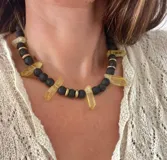 Collar corto con cuentas de piedra volcánica negra, separadores dorados y cristales de cuarzo amarillo.