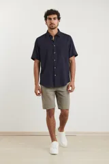 Camisa sport de manga corta color verde oliva, línea premium, con cuello clásico, cierre frontal con botones de coco y bolsillo de parche en el pecho. Confeccionada en lino y algodón.