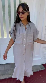 Vestido camisero largo color beige claro, de lino, con cuello mao, mangas cortas y bolsillos delanteros. Tiene botones de nácar.