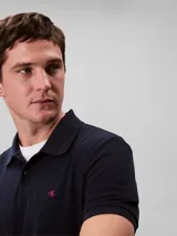 Chomba de piqué de algodón color azul marino, corte clásico, cuello polo con dos botones y logo CK bordado en rojo en el pecho.