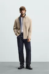 Sobrecamisa negra de tejido con elasticidad, cuello solapa, manga larga con puño abotonado, bolsillos de plastrón en el pecho y cierre frontal con botones a presión.