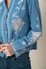 Camisa de jean celeste con bordados de flores blancas en hilo de seda, cuello mao y cierre frontal con botones.