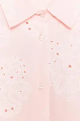 Camisa manga larga color rosa pálido con cuello solapa y cierre frontal con botones. Detalle de bordados perforados engomados con motivos florales. Corte recto.