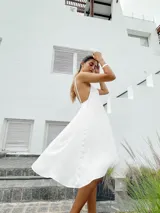 Vestido corto color naranja, con escote halter y diseño asimétrico con capas. Espalda con tiras regulables.