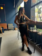 Pollera larga de cuero con flecos en el borde, ajustada a la cintura y diseño casual.