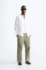 Camisa color beige claro, de corte relaxed fit, confeccionada en tejido de lino y algodón. Tiene cuello mao, manga larga con puños abotonados y cierre frontal con botones.