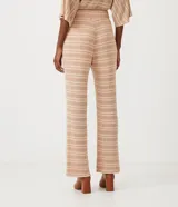 Pantalón largo de tejido de punto con rayas horizontales en tonos beige y marrón claro. El pantalón es de corte flare, con cintura alta y lazo para ajustar.