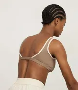 Top deportivo color marrón con breteles anchos y doble tira, copa desmontable, detalles contrastantes en color crema, escote en U delantero y escote en V en la espalda. Confeccionado en microfibra.