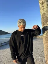 Buzo negro oversize con cuello redondo y logo ovalado bordado en el pecho.