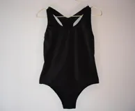 Malla enteriza lisa de color negro, confeccionada con tela que incluye fibra LYCRA® XTRA LIFE™.