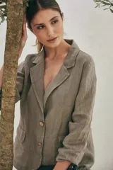 Blazer color gris topo de lino con solapas de muesca, cierre frontal con dos botones de madera, bolsillos de parche y mangas largas.