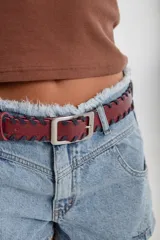 Cinto de cuero color bordó con costuras de tientos en los bordes y hebilla metálica plateada.