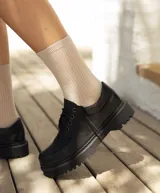 Zapato acordonado de cuero negro con suela track.