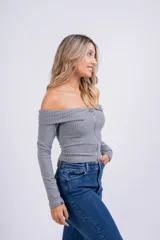 Remera blanca de punto canalé con escote off-shoulder y cierre frontal con cremallera metálica.