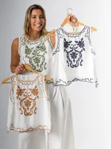Musculosa blanca con bordado floral verde en el frente, cuello redondo y corte holgado.
