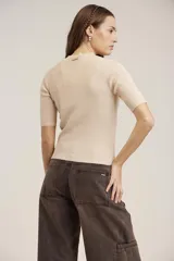 Blusa de punto color beige, de mangas cortas y cuello alto.