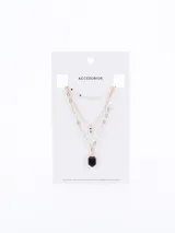 Collar dorado de tres cadenas, la primera con eslabones pequeños, la segunda con un dije circular y la tercera con un dije de piedra facetada negra.