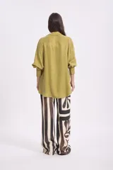 Camisa color verde oliva, de corte recto, con cuello camisero y mangas largas con puños abotonados.