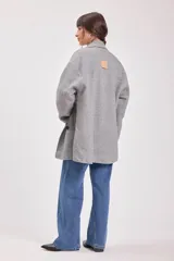 Tapado gris de lana con doble botonadura, cuello con solapas y bolsillos laterales.