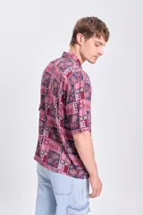 Camisa de manga corta con estampado de palmeras en tonos bordó y azul.