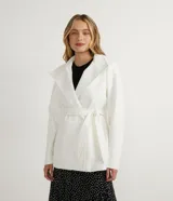 Campera alargada color blanco, confeccionada en polivelour, con cuello alto doblable, mangas largas, abotonado frontal doble, bolsillos y cinturón.