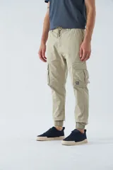 Pantalón cargo color marrón con corte slim, elástico en cintura y cordón ajustable, bolsillos cargo con botones y puños elásticos. Confeccionado en algodón y spandex.