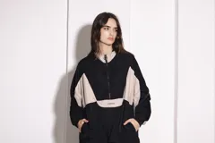 Campera deportiva negra y beige con cierre frontal, cuello alto, puños ajustados y ruedo regulable.