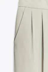 Pantalón color verde claro de tiro alto, con bolsillos delanteros, cintura elástica en la parte trasera y cierre frontal con cremallera y botones.