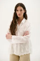 Camisa blanca con bordado floral, de corte holgado y manga larga.