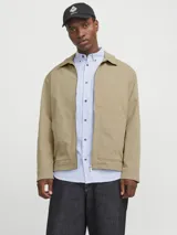 Sobrecamisa shacket color beige con cierre de cremallera y diseño resistente. Confeccionada en tejido liviano, delgado y transpirable de poliéster reciclado. Presenta cuello clásico, mangas largas con puños abotonados, cierre con cremallera y bolsillos frontales funcionales.