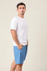 Bermuda deportiva de nylon color verde oliva, de corte suelto, con cintura elástica y cordón de ajuste. Cuenta con detalles de líneas verticales en los costados y bolsillos laterales con cierre.