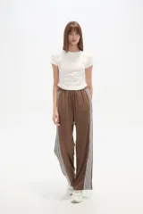 Pantalón de algodón negro, holgado, de calce medio, con cintura elástica y cordón ajustable. Presenta tres rayas blancas verticales en los laterales.