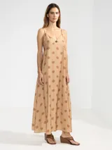 Vestido largo color beige con estampado de flores marrones y rayas verticales. Tiene breteles finos, escote en V y detalle de flor en el centro.
