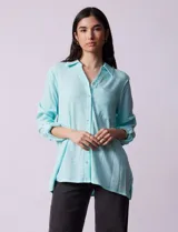 Camisa celeste texturada con cuello con solapa y abertura central con botones. Delantera con bolsillo aplicado y largo de manga regulable con presilla y botón.