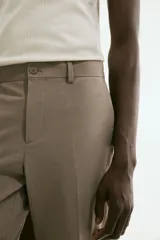 Pantalón de vestir color beige, corte slim fit, con cierre de botón, bolsillos laterales y bolsillos traseros ribeteados con botón.