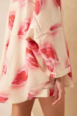 Camisa oversize de lino con estampado de labios en tonos rosados y rojos. Tiene cuello clásico, cierre frontal con botones y mangas largas. Detalles de calado en los bordes. Completa el conjunto con el Short Lipstick.
