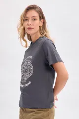 Remera gris con cuello redondo y manga corta. Estampado frontal con dos serpientes entrelazadas y texto en blanco que dice 'Not everything is what it seems'.
