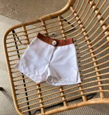 Short blanco de tiro alto con cintura marrón y botón decorativo.