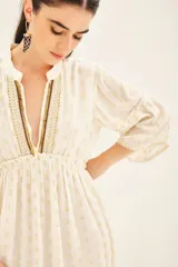 Vestido corto color blanco con estampado de lunares dorados, escote en V con detalle de bordado y mangas al codo con volantes.