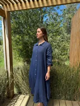 Vestido camisero amplio y largo de lino color azul, con botones de nácar, cuello camisero y bolsillos laterales.