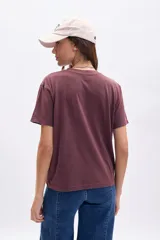 Remera de manga corta color marrón oscuro con efecto gastado, corte holgado y estampado frontal de Minnie Mouse dentro de un corazón blanco con texto en azul.