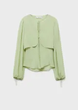 Blusa color verde claro de gasa semitransparente, con cuello redondo con lazos, mangas largas abullonadas con puños elásticos y diseño combinado.