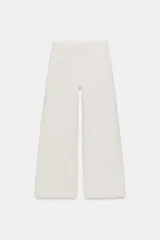 Jeans de tiro alto con diseño wide leg y largo completo. Presentan una estructura de cinco bolsillos, cintura con trabillas y cierre frontal con cremallera y botón. El diseño destaca por su patrón de rayas verticales a contraste sobre fondo claro.