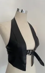 Top negro tipo halter de cuero sintético con escote en V y hebilla metálica en la cintura.